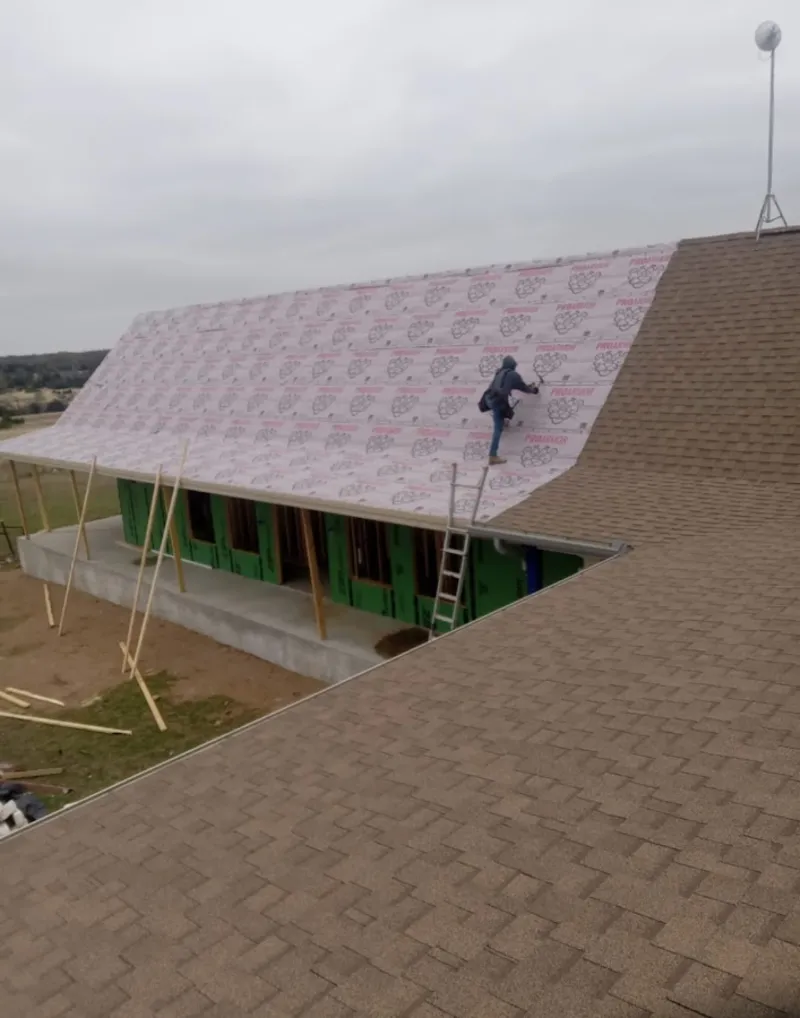 Worker preparing underlayment for a metal roof installation in Elmwood